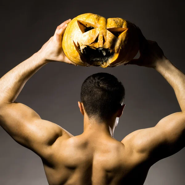 Homme musclé en masque avec citrouille — Photo