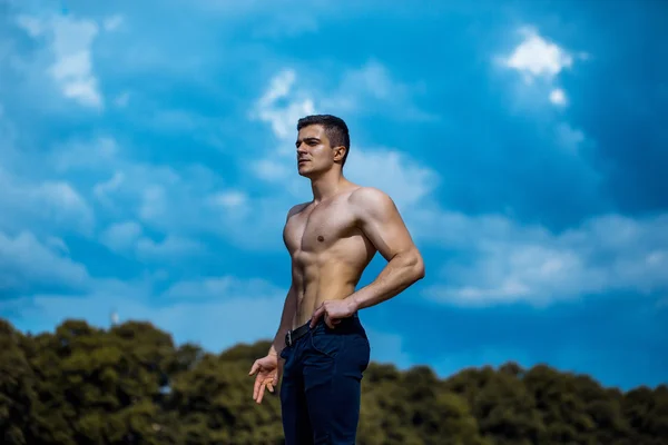 Sexy muscular man on blue sky — Stock Photo, Image