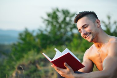 Kitap açık ile gülümseyen kaslı adam