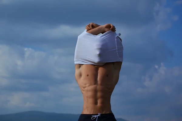 Sexy muskulöser Mann zieht sich am Himmel aus — Stockfoto