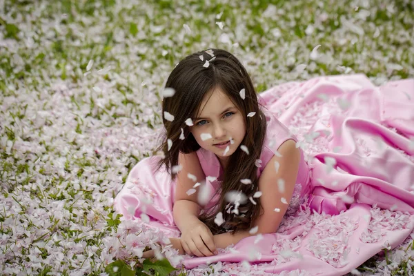 꽃잎과 푸른 잔디에 어린 소녀 — 스톡 사진