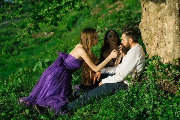 Bearded man and two women on grass — Stock Photo, Image