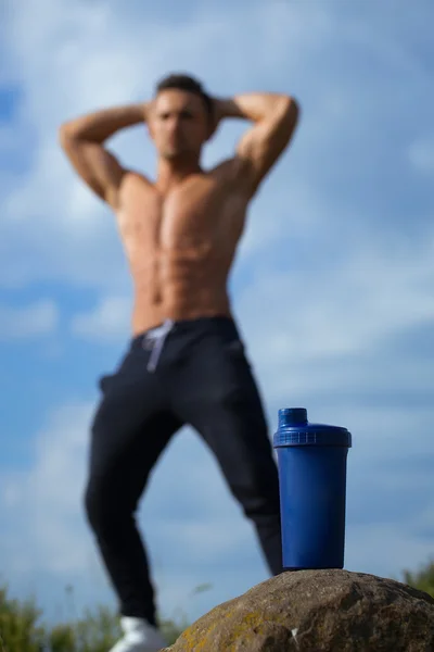 Мышечный человек позирует возле бутылки с водой — стоковое фото