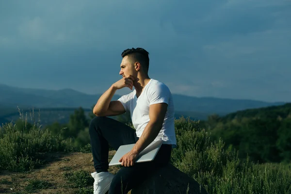 Dizüstü bilgisayar açık ile dalgın kaslı adam — Stok fotoğraf