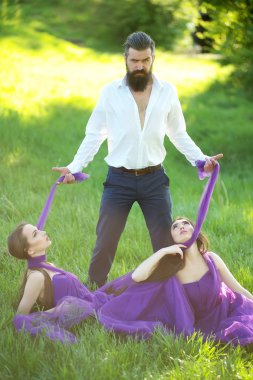 Sakallı adam ve iki kadınla çimenlerin üzerinde