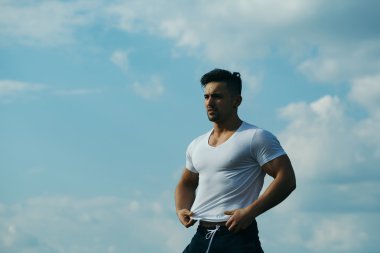 Gökyüzü arka plan üzerinde seksi kaslı adam