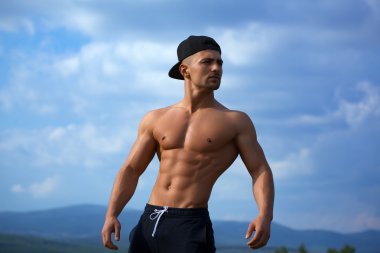 Gökyüzü arka plan üzerinde seksi kaslı adam