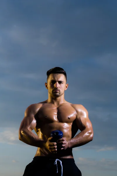 Влажный мускулистый человек с бутылкой воды — стоковое фото