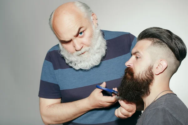 Old hairdresser and young bearded man
