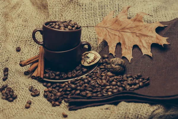 Cup with coffee beans and oak leaf — Stock Photo, Image