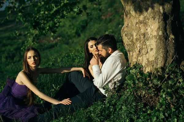 Bearded man and two women on grass — Stock Photo, Image