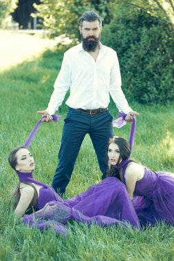 Sakallı adam ve iki kadınla çimenlerin üzerinde