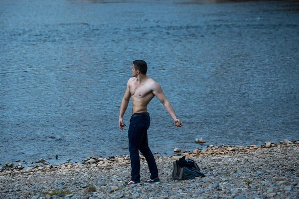 Muscular man with bag near water — Stock Photo, Image