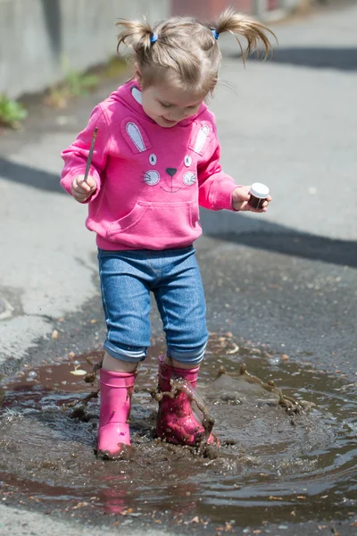 Kleines Mädchen in Gummistiefeln im Buddel — Stockfoto