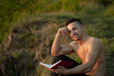 Kitap açık ile gülümseyen kaslı adam