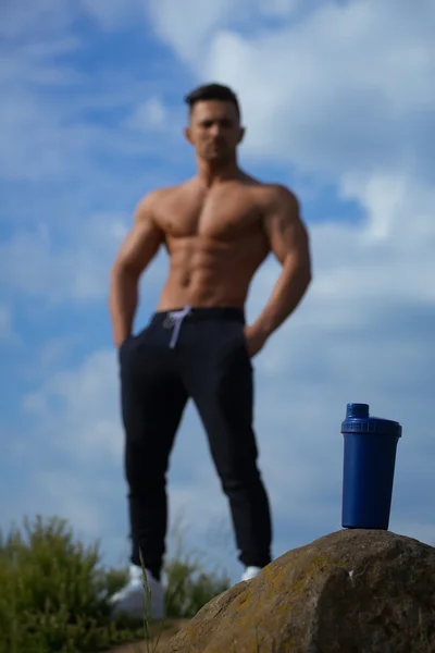 Muscular man posing near water bottle — Stock Photo, Image