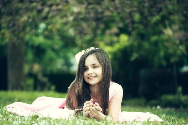 Petite fille sur herbe verte avec des pétales — Photo