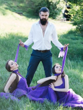 Sakallı adam ve iki kadınla çimenlerin üzerinde