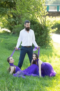 Sakallı adam ve iki kadınla çimenlerin üzerinde