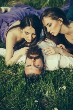 Sakallı adam ve iki kadınla çimenlerin üzerinde