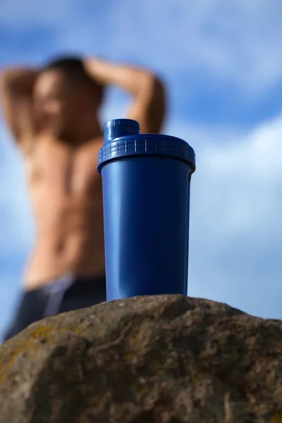 Мышечный человек расслабляется возле бутылки с водой — стоковое фото
