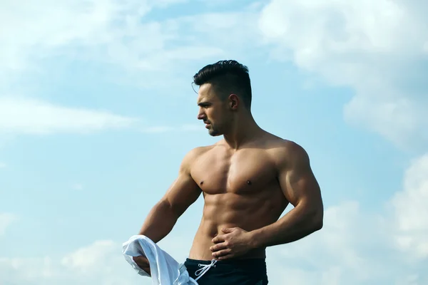 Sexy muscular man undressing on sky background — Stock Photo, Image