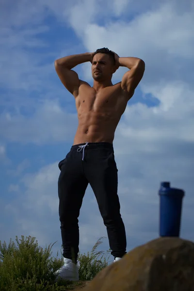 Muskulöser Mann posiert in der Nähe einer Wasserflasche — Stockfoto