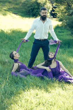 Sakallı adam ve iki kadınla çimenlerin üzerinde