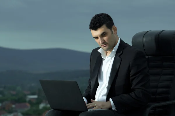 Бизнесмен с ноутбуком на стуле — стоковое фото