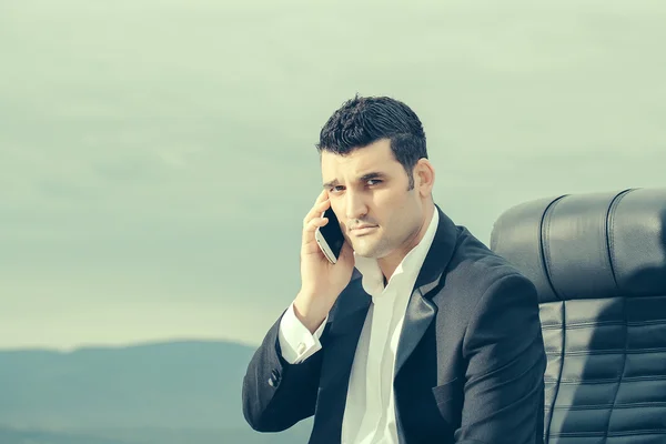 Бизнесмен с телефоном на стуле открытый — стоковое фото