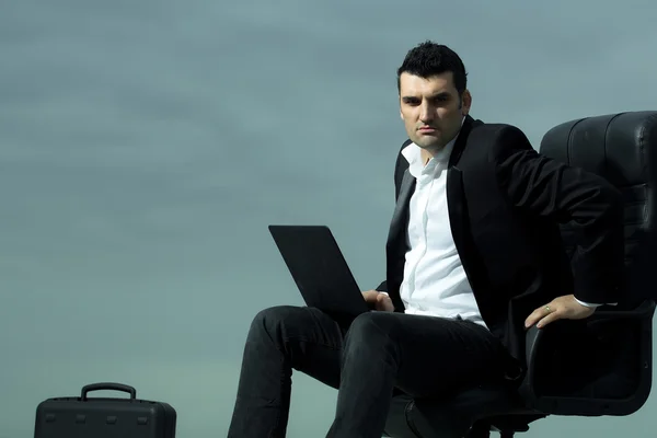 Бизнесмен с ноутбуком на стуле — стоковое фото
