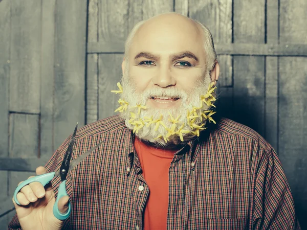 old man with flowers in beard and scissors