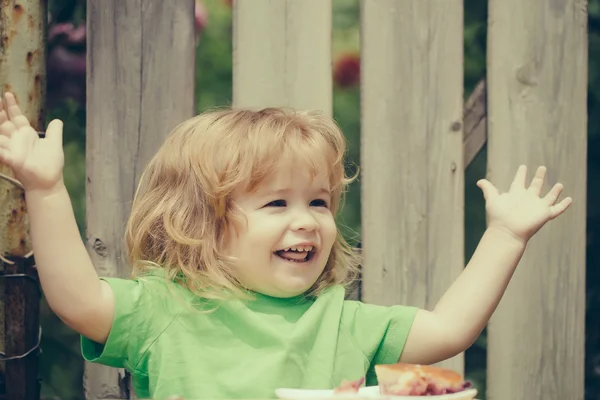 木製のフェンス近くのパイを食べる小さな男の子 — ストック写真