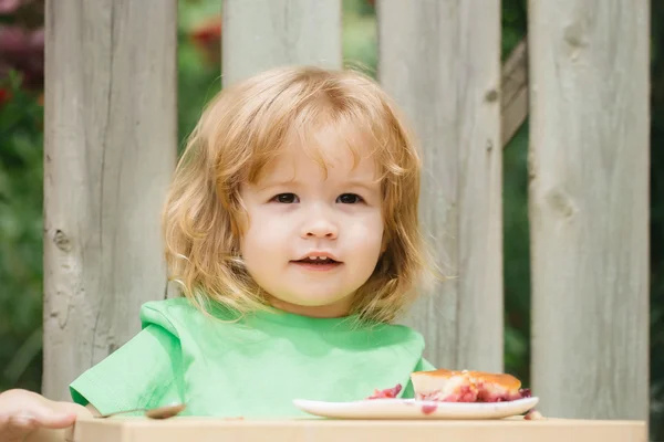 Liten pojke äta paj nära planket — Stockfoto