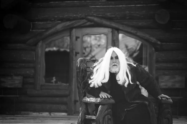 Velho feiticeiro em cadeira de madeira — Fotografia de Stock