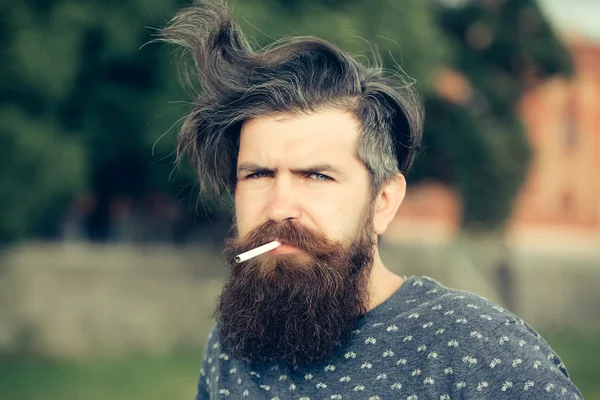 Бородатый мужчина курит сигарету на открытом воздухе — стоковое фото