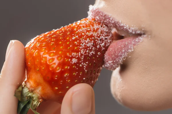 Vrouwelijke suikerlippen bijten rode aardbei — Stockfoto