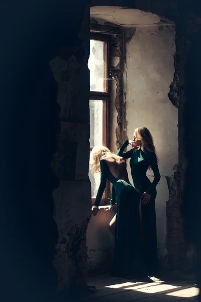 Vackra kvinnor i gröna klänningar nära fönster — Stockfoto