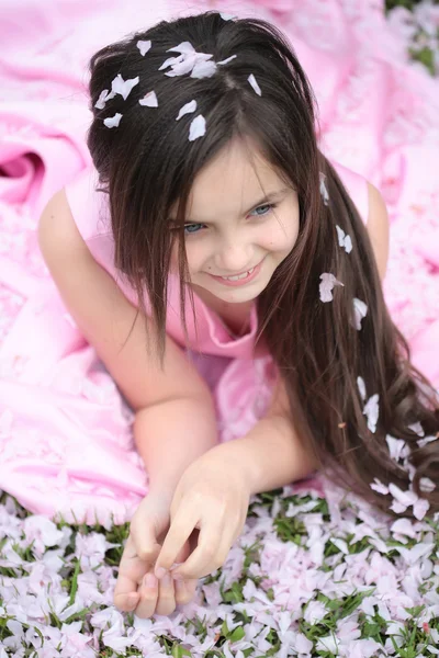 Niña sobre hierba verde con pétalos —  Fotos de Stock