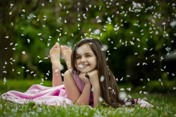 Menina na grama verde com pétalas — Fotografia de Stock