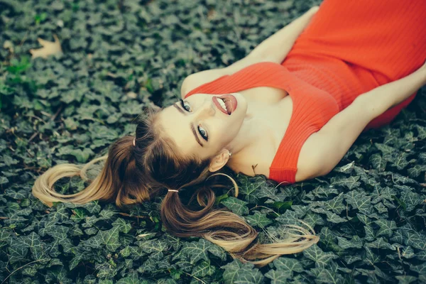 Smiling girl lying on green leaves — Stock Photo, Image