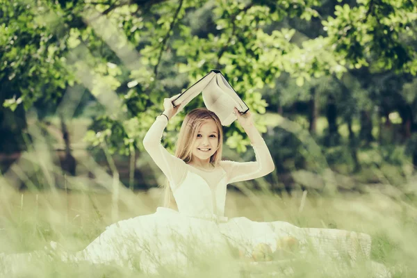 Liten flicka i klänning med fruktkorg och bok — Stockfoto