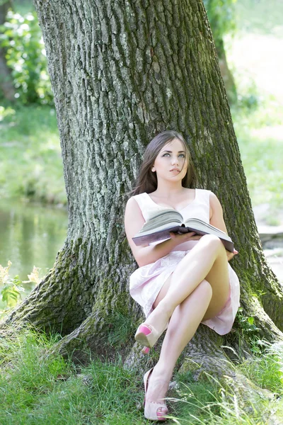 Bonita mujer leyendo libro sobre hierba — Foto de Stock