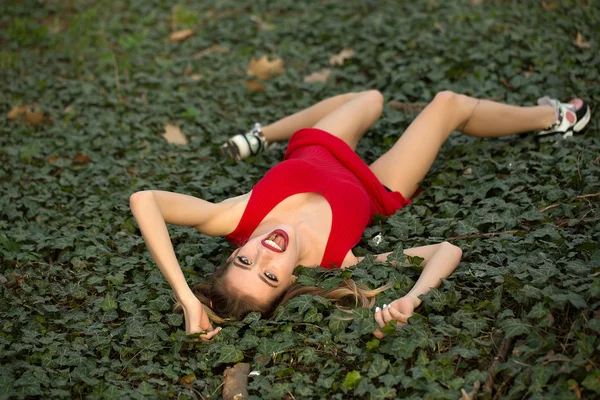 Lachende meisje liggend op groene bladeren — Stockfoto