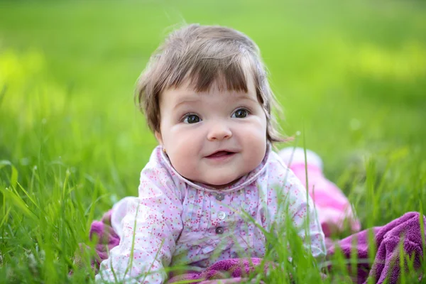 Niedliches kleines Mädchen auf grünem Gras — Stockfoto