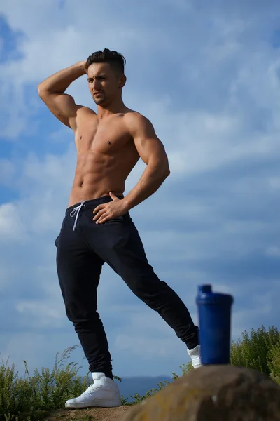 Muscular man posing near water bottle — Stock Photo, Image