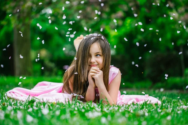 Menina na grama verde com pétalas — Fotografia de Stock