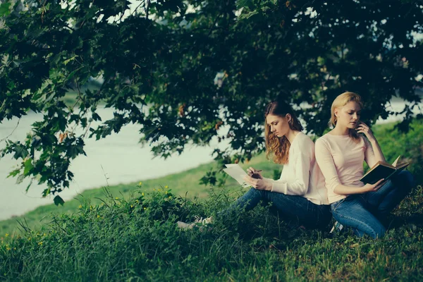 Twee meisjes zitten op gras — Stockfoto