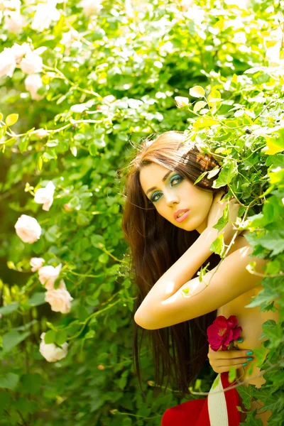 Sexig kvinna med röd hatt nära rosenbuske — Stockfoto