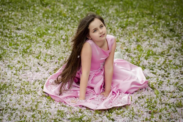 Petite fille sur herbe verte avec des pétales — Photo